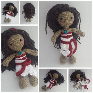 K&ouml;nnte beinhalten: H&auml;kelpuppe mit braunen Haaren, einem wei&szlig;en und roten Kleid und einer t&uuml;rkisfarbenen Halskette. Die Puppe tr&auml;gt einen wei&szlig;en und roten Rock mit einer roten Sch&auml;rpe.