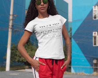 May include: White t-shirt with black text that reads "YES, I'M TALL THAT'S A VERY UNUSUAL GIFT OF GOD NO I DON'T PLAY BASKETBALL THE WEATHER IS PERFECT UP HERE". A person is wearing the t-shirt with red pants that have white stripes down the sides.