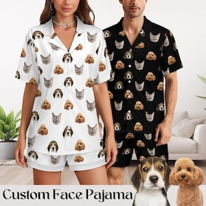 May include: Two matching pajama sets, one white and one black, are patterned with dog and cat faces. The white set is worn by a person, and the black set is worn by another person. The text "Custom Face Pajama" is at the bottom of the image.