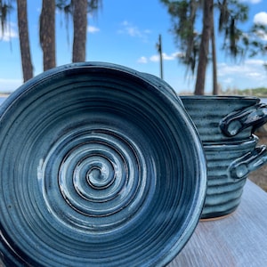 Puede incluir: Tres cuencos de cer&aacute;mica azul con un dise&ntilde;o en espiral. Los cuencos est&aacute;n apilados uno encima del otro. Los cuencos son hechos a mano y tienen un aspecto r&uacute;stico.