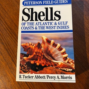 May include: A Peterson Field Guide book titled "Shells of the Atlantic & Gulf Coasts & the West Indies" with a close-up image of a large seashell on the cover. The book is written by R. Tucker Abbott and Percy A. Morris.