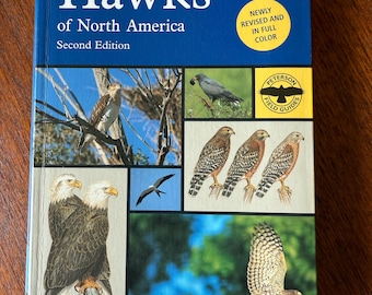 May include: A field guide titled "Hawks of North America" by William S. Clark and Brian K. Wheeler. The book features a blue cover with images of various hawks and the text "NEWLY REVISED AND IN FULL COLOR". The Peterson Field Guides logo is visible.