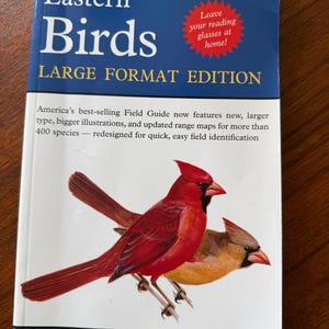May include: A Peterson Field Guides book titled Eastern Birds Large Format Edition. The cover features a red cardinal and a brown bird, with text stating Leave your reading glasses at home and America's best-selling Field Guide by Roger Tory Peterson.
