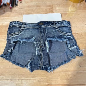 May include: A pair of denim shorts with a frayed hem. The shorts are a light blue wash and have a button and zip closure.