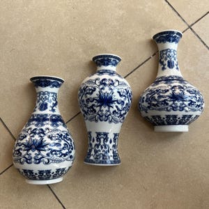 May include: Three blue and white porcelain vases with intricate floral and geometric designs. The vases are of varying sizes and shapes, with a classic Chinese aesthetic.
