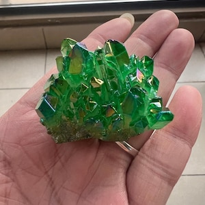 以下が含まれることがあります： 虹色の輝きを持つ緑色の虹色水晶のクラスター。結晶は自然な形で集まっています。