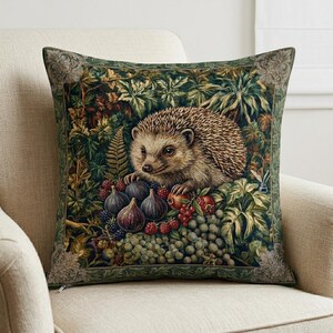 May include: Square decorative pillow featuring a detailed illustration of a hedgehog amidst lush foliage, figs, grapes, and berries. The pillow has a dark green border with an ornate design, creating a nature-inspired theme.