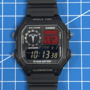 May include: Black digital watch with a rectangular face and black band. The watch face displays the time, date, and other functions. The watch has the text "CASIO" and "10 YEAR BATTERY" printed on the face.