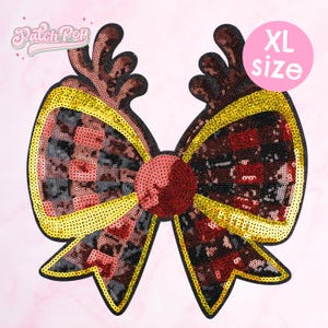 May include: An XL size sequined bow patch in shades of red, black, and gold. The bow features a checkered pattern in the center and a large, round sequined centre. The edges are outlined in gold sequins. The patch has the text "Patch Pop" and "XL size".