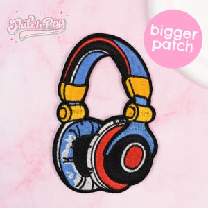May include: Embroidered patch featuring a stylized pair of headphones. The headphones have blue earcups, a red and black center, and a blue headband with red and black accents. The patch has yellow and black details and the text "Patch Pop" and "bigger patch".