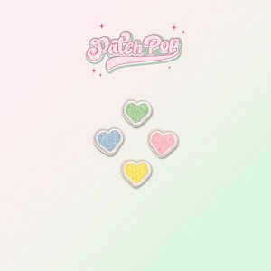 May include: Four heart-shaped embroidered patches in pastel colors: blue, green, pink, and yellow. Each patch has a white border. The image also includes the text "Patch Pop" in a retro font.