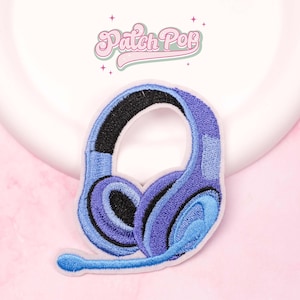 Puede incluir: Parche bordado con unos auriculares azules y negros con micrófono. El parche tiene un borde blanco y el texto "Patch Pop" en rosa, en cursiva.