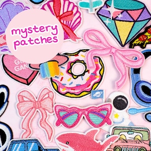 以下が含まれることがあります： ピンク色の背景に、カラフルな刺繍パッチのコレクション。パッチには、ピンクのドーナツ、ダイヤモンド、リボン、サングラス、サメ、宇宙飛行士が含まれます。「mystery patches」というテキストがピンク色の円の中にあります。