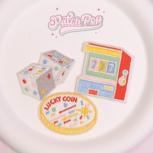Könnte beinhalten: Gestickte Aufnäher mit Würfeln, einem Spielautomaten mit der Zahl 777 und einem "Lucky Coin"-Design. Die Aufnäher sind farbenfroh mit einem Retro-Look, ideal zum Aufnähen auf Kleidung oder Accessoires.