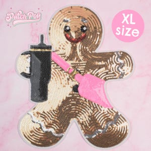 Può includere: Toppa a forma di omino di pan di zenzero con paillettes di taglia XL con un bicchiere nero e un pennello rosa. La toppa ha un bordo bianco e il testo "Patch Pop" in rosa.