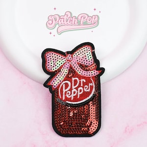 Op de afbeelding: Een pailletten patch met een rode Dr. Pepper fles met een roze strik. De patch heeft een zwarte rand en de woorden "Dr. Pepper" in witte letters. De patch staat op een witte achtergrond met de tekst "Patch Pop" in roze.