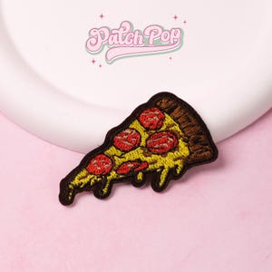 Könnte beinhalten: Gestickter Pizza-Scheiben-Aufnäher mit gelbem Käse, roter Peperoni und braunem Kruste. Der Aufnäher hat einen schwarzen Rand und den Text "Patch Pop" in Rosa.