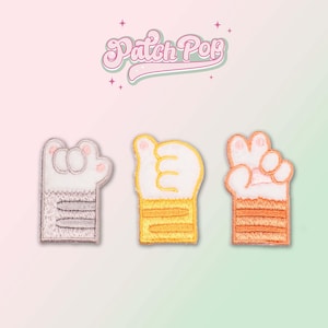 Puede incluir: Tres parches bordados para planchar que representan una pata de gato de dibujos animados en diferentes colores. Los parches tienen la forma de una pata con tres dedos. El primer parche es gris con almohadillas blancas, el segundo es amarillo con almohadillas blancas y el tercero es naranja con almohadillas blancas. Los parches miden aproximadamente 5 cm de alto.