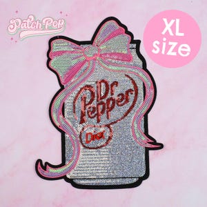 May include: XL size sequined patch in the shape of a Dr. Pepper soda can with a pink bow. The can is silver with the words "Dr Pepper" in red sequins. The word "Diet" is also visible. The patch has a black border.