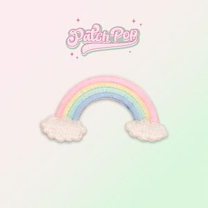 Könnte beinhalten: Ein gestickter Patch in Form eines Regenbogens mit weißen Wolken auf beiden Seiten. Der Patch befindet sich auf einem hellrosa und grünen Hintergrund mit dem Text "Patch Pop" in einer Retro-Schrift.