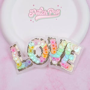 May include: A sequined "LOVE" patch in rainbow colors, with gold trim, on a white mesh backing. The patch is set against a pink background. The logo "Patch Pop" is visible in the top center.