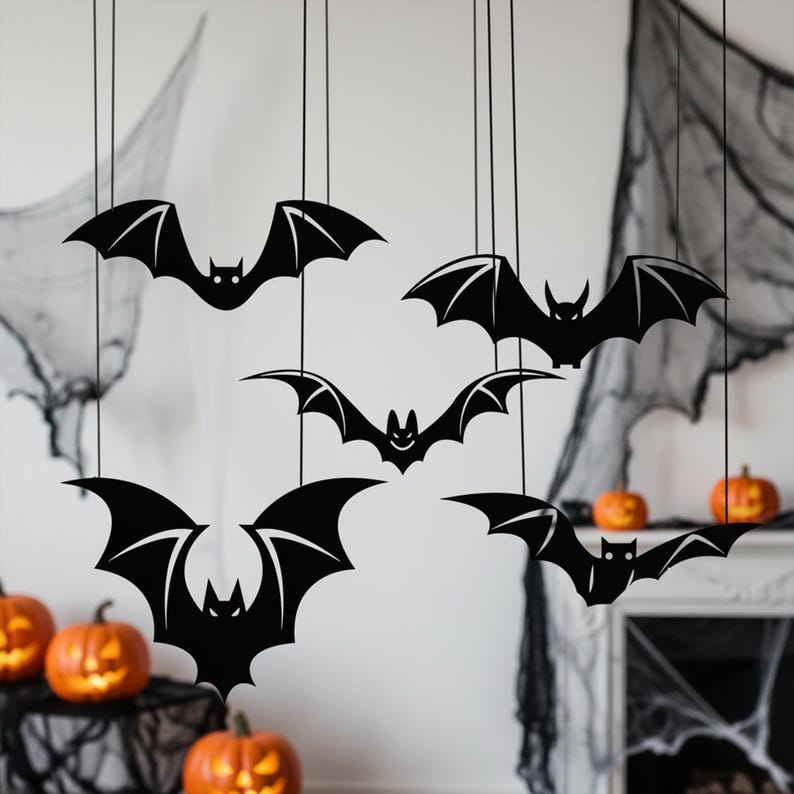Pu&ograve; includere: Decorazioni a forma di pipistrello nero appese a fili, perfette per Halloween. I pipistrelli hanno ali dettagliate e sono sospesi davanti a un muro bianco con zucche e ragnatele. Una decorazione festosa e spettrale.