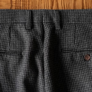 K&ouml;nnte beinhalten: Nahaufnahme der R&uuml;ckseite einer Hose mit grauem und schwarzem Muster. Die Hose hat zwei Ges&auml;&szlig;taschen, G&uuml;rtelschlaufen und einen Knopfverschluss. Der Stoff hat ein subtiles strukturiertes Aussehen.