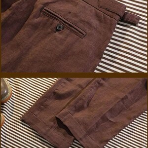 Pu&ograve; includere: Primo piano di pantaloni di lino marroni. I pantaloni hanno una tasca posteriore con bottoni e un dettaglio di passanti per cintura. Il tessuto ha un aspetto strutturato. I pantaloni sono piegati su uno sfondo a righe.