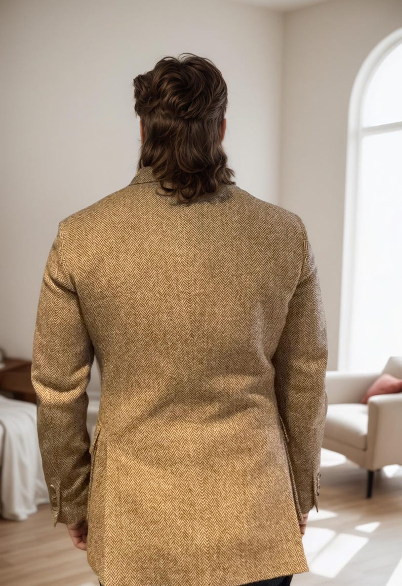 May include: A tan herringbone blazer with a classic design. The jacket has a two-button closure and a notched lapel. The fabric has a subtle pattern and a tailored fit. The person is facing away from the camera.