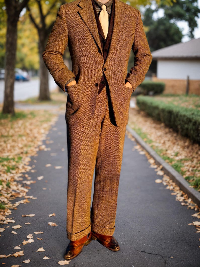 May include: A brown tweed suit with a matching blazer and trousers. The suit features a notched lapel, a two-button closure, and pockets. The person is wearing a brown vest, a yellow tie, and brown leather shoes. The suit is worn on a paved walkway.