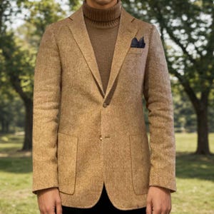May include: A tan herringbone blazer with a single-button closure and two front pockets. The blazer is paired with a brown turtleneck sweater and a navy pocket square. The outfit is suitable for a business casual or smart casual look.