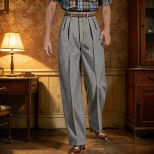 May include: High-waisted grey trousers featuring double pleats at the front, a wide-leg silhouette, and a brown leather belt with a silver-toned buckle. The trousers are crafted from a textured grey fabric and include cuffed hems at the bottom.