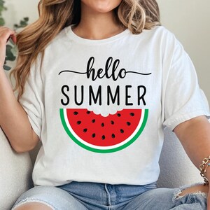 Peut inclure: T-shirt blanc avec l'inscription "hello SUMMER" en noir et un motif de past&egrave;que. La past&egrave;que est rouge avec des graines noires et une peau verte. Un haut d'&eacute;t&eacute; d&eacute;contract&eacute;.