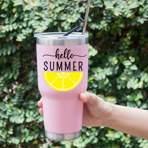 Peut inclure: Un gobelet isotherme rose avec un bord et un couvercle argent&eacute;s. Le gobelet porte les mots "hello SUMMER" en &eacute;criture noire au-dessus d'un graphique de tranche de citron jaune. Une paille et un support noirs sont ins&eacute;r&eacute;s dans le couvercle.