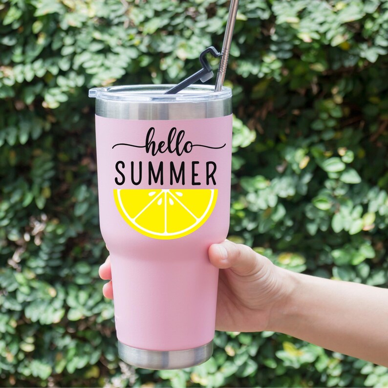 Peut inclure: Un gobelet isotherme rose avec un bord et un couvercle argent&eacute;s. Le gobelet porte les mots "hello SUMMER" en &eacute;criture noire au-dessus d'un graphique de tranche de citron jaune. Une paille et un support noirs sont ins&eacute;r&eacute;s dans le couvercle.