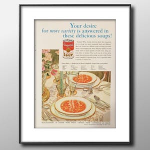 May include: A framed vintage advertisement for Campbell's Vegetable Soup. The ad features a can of soup, two bowls of soup on a table setting, and text that reads "Your desire for more variety is answered in these delicious soups!"