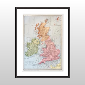 May include: Framed vintage map of the British Isles, featuring detailed geographical information. The map is in shades of pink, green, and orange, with a blue background. The title "British Isles" is printed at the bottom. The map is framed in a black frame.