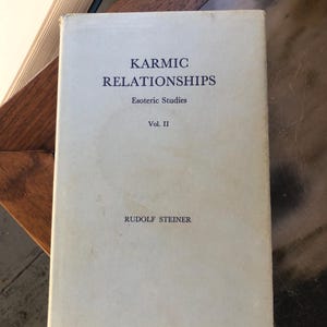 May include: A vintage book titled "Karmic Relationships" by Rudolf Steiner. The book's cover is a light blue-gray with dark blue text. The book is part of the "Esoteric Studies" series, Volume II.