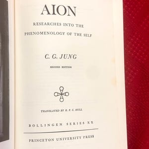 May include: Open book with the title "AION" and the subtitle "Researches Into The Phenomenology Of The Self." The author is C.G. Jung. The book is a second edition, translated by R.F.C. Hull, and published by Princeton University Press.
