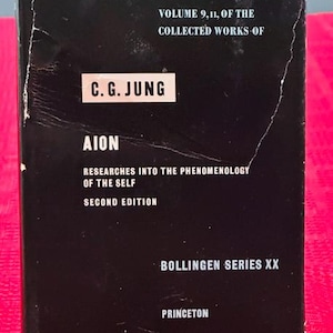 May include: A black book with white text. The cover reads "Volume 9, 11, of the Collected Works of C.G. Jung." The title "Aion" is displayed prominently, with "Researches into the Phenomenology of the Self" below it. The book is a second edition from Princeton.