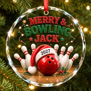 May include: A circular glass Christmas ornament featuring a red bowling ball wearing a white-trimmed red Santa hat with the year 2027 printed on it. The text MERRY & BOWLING JACK is displayed above several white bowling pins with red stripes.