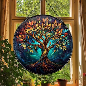 May include: A stained glass window hanging in a window frame. The window features a colourful tree of life design with a dark blue background. The tree has a thick trunk and branches with leaves in shades of yellow, orange, red, green, and blue. The roots of the tree are visible at the bottom of the window.