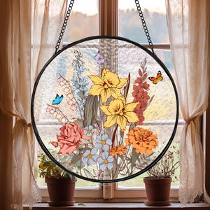 May include: A round stained glass window hanging from a chain. The design features a bouquet of yellow daffodils, orange and red flowers, and blue butterflies.