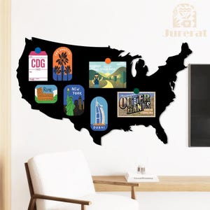 Peut inclure: Une décoration murale noire en forme de carte des États-Unis avec des aimants colorés sur le thème du voyage. Les aimants représentent des destinations telles que Paris, Los Angeles, Rome, New York, Dubaï et Outer Banks. Décoration murale sur fond blanc.