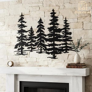 May include: Black metal wall art depicting a forest scene with several pine trees. The artwork is mounted on a light-colored stone wall above a white fireplace mantel. A small clock, books, and a vase with greenery are also on the mantel.