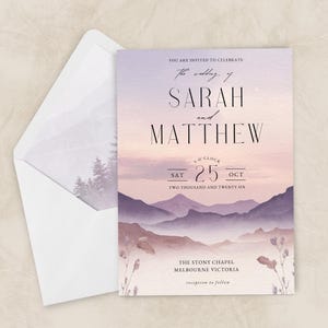 Può includere: Invito di nozze con un design paesaggistico ad acquerello nei toni del viola, rosa e beige. L'invito include i nomi "SARAH e MATTHEW", la data "SAT 25 OCT" e la location "THE STONY CHAPEL MELBOURNE VICTORIA". È inclusa una busta abbinata.