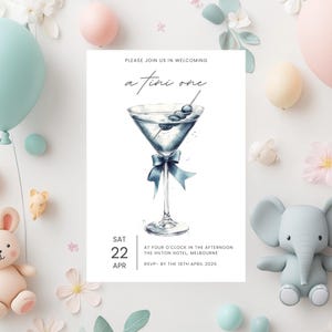 May include: A blue and white illustrated martini glass with olives on a toothpick. The text reads "Please join us in welcoming a fini one" and "Sat 22 Apr. At four o'clock in the afternoon. The Hilton Hotel, Melbourne. RSVP - by the 16th April 2025."