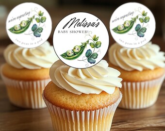 Op de afbeelding: Drie cupcakes versierd met ronde, witte papieren cirkels. De cirkels hebben een ontwerp met een groene erwtenschil met twee erwten erin. De tekst op de cirkels luidt "we're expecting two peas in a pod" en "Melissa's Baby Shower!"