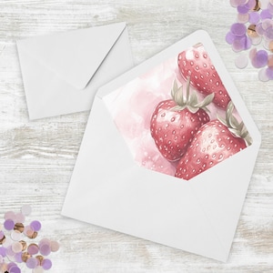 May include: White envelopes with a watercolor design of ripe strawberries inside. The strawberries are red with green stems and leaves, set against a pink background. Confetti in shades of purple and gold are scattered around the envelopes.