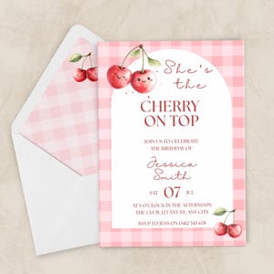 Puede incluir: Una invitación de cumpleaños rosa con estampado de cuadros vichy con el texto "She's the Cherry on Top". La invitación presenta ilustraciones de acuarela de cerezas y va acompañada de un sobre a juego.